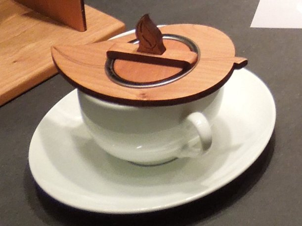 A tea infuser in a teacup, with a wooden lid