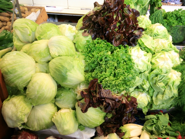 A selection of lettuces with whitish iceberg lettuce heads on the left